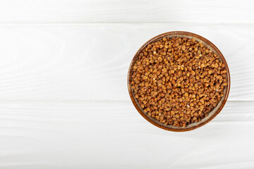 Raw buckwheat in a bowl on a textured background.Wheat grains, porridge, cereals, raw buckwheat in a plate. Healthy food. Porridge. Diet. Organic cerea. Space for text.Copy space.