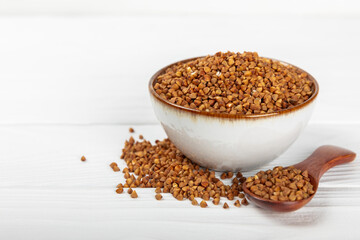Raw buckwheat in a bowl on a textured background.Wheat grains, porridge, cereals, raw buckwheat in a plate. Healthy food. Porridge. Diet. Organic cerea. Space for text.Copy space.