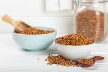 Raw buckwheat in a bowl on a textured background.Wheat grains, porridge, cereals, raw buckwheat in a plate. Healthy food. Porridge. Diet. Organic cerea. Space for text.Copy space.