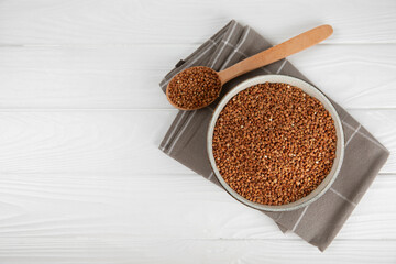 Raw buckwheat in a bowl on a textured background.Wheat grains, porridge, cereals, raw buckwheat in a plate. Healthy food. Porridge. Diet. Organic cerea. Space for text.Copy space.