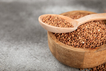 Raw buckwheat in a bowl on a textured background.Wheat grains, porridge, cereals, raw buckwheat in a plate. Healthy food. Porridge. Diet. Organic cerea. Space for text.Copy space.