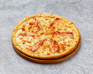 Homemade Italian style pizza with cheese, bacon and chicken close-up on a wooden board on the table. Horizontal