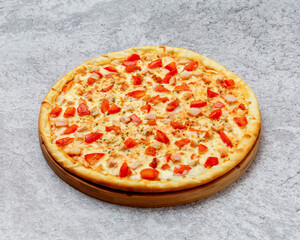 Homemade Italian style pizza with cheese, chicken and tomatoes close-up on a wooden board on the table. Horizontal