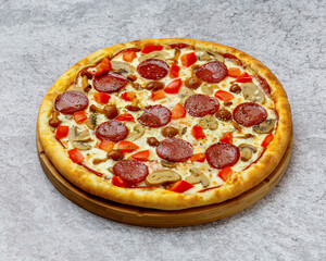 Homemade Italian style pizza with cheese, mushrooms, champignons, sausage and tomatoes close-up on a wooden board on the table. Horizontal