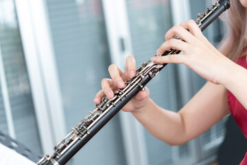 Beautiful young woman in a red dress playing the clarinet .,Classical musician oboe playing..