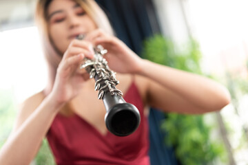 Beautiful young woman in a red dress playing the clarinet .,Classical musician oboe playing..