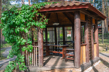 A gazebo made of wooden logs for relaxing in the forest and protection from sunlight and rain. A gazebo for people to relax during vacations and weekends outdoors in summer. Wooden gazebo in the park.