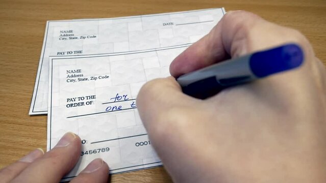 Hand sign a bank check on wooden table background, Blank bank cheque, Prepare writing a check, closeup,