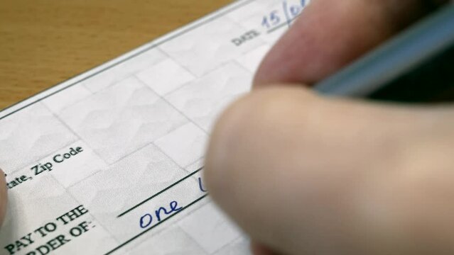 Hand sign a bank check on wooden table background, Blank bank cheque, Prepare writing a check, closeup,