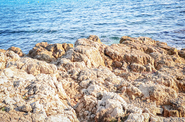 Fototapeta na wymiar Giant rock textured cliff edge isolated on sea waves background on sunny day sunlight.