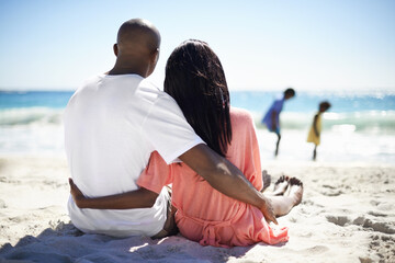 Black family, relaxing on beach and hug with back, sand and married for summer vacation. African,...