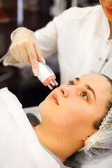 Naklejka premium Crop beautician using machine for radiofrequency lifting
