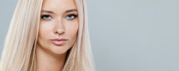 Gorgeous blonde woman with long straight hair and clean fresh pure perfect skin isolated on gray...