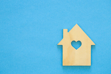 Fototapeta na wymiar Wooden house model on blue background. House sale or rent, family home and shelter concept, real estate and eco accommodation. Copy space.