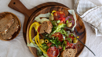 wooden plate with chorizo salad on the table