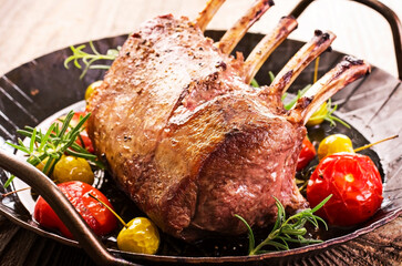 Traditional barbecue carree of venison with fruits and tomatoes served as close-up on a classic...