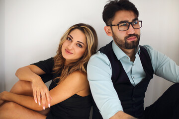 Stylish young ethnic couple embracing against light gray wall