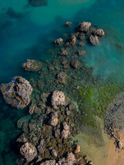 Rock formation in turquoise sea with golden beach sand in Malta aerial top down. Vertical background photo. Natural colors palette in Mediterranean sea paradise.