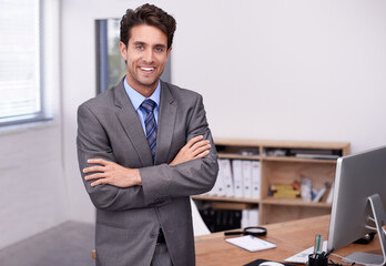 Portrait of confident businessman at desk with smile, arms crossed and career in legal inspection at law firm. Happy attorney, lawyer or business man with office job as quality assurance professional