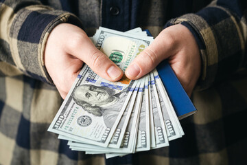 Passport and dollar bills in male hands, money close-up, concept of credit, migration and tourism.