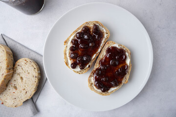 Whole grain bread with strawberry jam on top. Composition with delicious homemade jam on a plate. Breakfast and snack concept.
