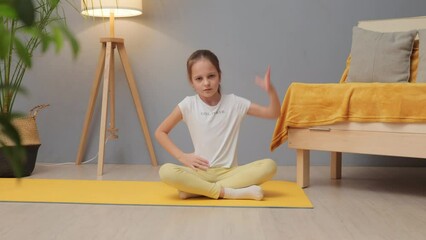 Leisure activities for children. Yoga positions for kids. Caucasian little girl with brown hair and ponytail doing sports exercises warming up her body on mat at home