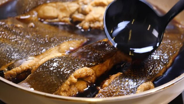 煮込んでいる子持ちカレイに煮汁を注ぐ動画。