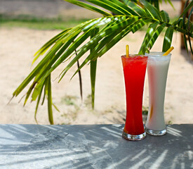 Tequila sunrise and pina colada cocktails under the palm