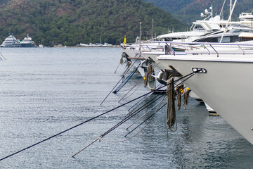 Row of super yachts moored in marina fore side view. Mediterranean yacht port with sailing boats....