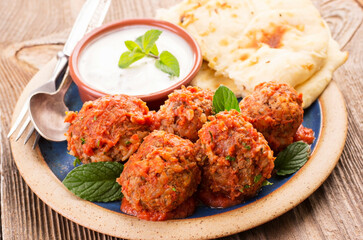 Traditional Persian slow cooked koofteh nokhod-chi meatballs with yoghurt and flatbread served as close-up on a design plate