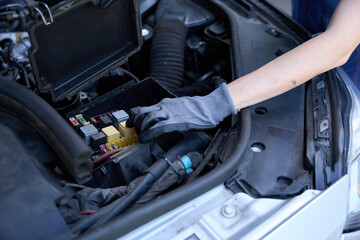 Woman in protective gloves works under the hood of car