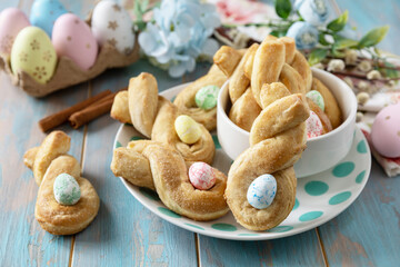 Easter rabbit-shaped buns puff pastry with  cinnamon on a wooden blue tabletop.
