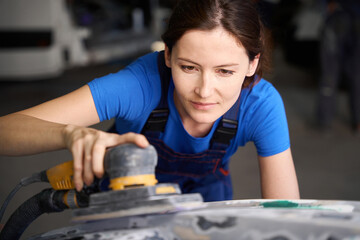 Specialist sands a car hood before painting