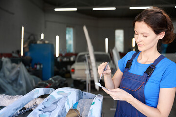 Young master puts putty on car parts before painting