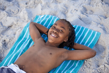 Naklejka premium Portrait, beach sand and towel with child to relax and summer holiday with sunshine in nature. Black teenager, face and smile for leisure on vacation, cape town and seaside for wellness in outdoor