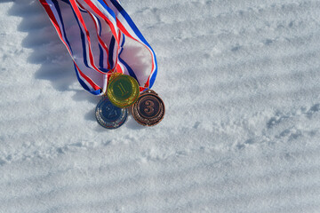 real Gold, silver and bronze medals hanging on red ribbons isolated lying on prepared, new snow ski...