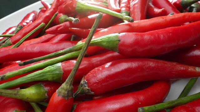 Witness the red chili peppers in exquisite detail, as their ridges and curves become a mesmerizing landscape in this macro video, showcasing the beauty of the small and spicy. Food concept. 
