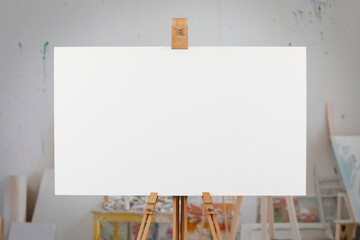 Blank canvas on an easel in an artist's studio.