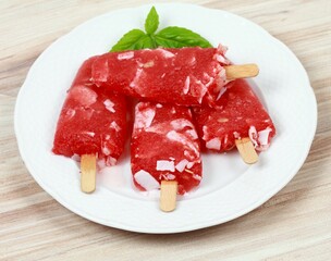 Homemade ice lolly from water melon with almond pieces. Delicious fruit popsicle with the stick on the plate.