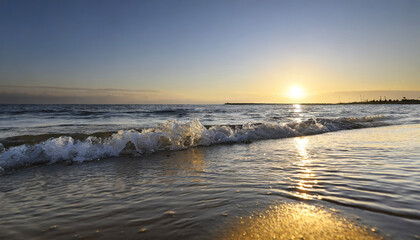 Obraz premium Close-up soft wave of the sea on the sandy beach with a sunset blue sky and cloud in summer background.