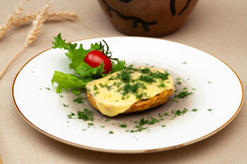 Baked potatoes with cheese and herbs on a plate