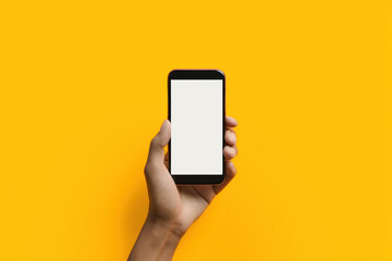 A male hand holds a modern black phone on a yellow isolated background. A digital device with a touch screen for the mockup. Generated by AI.