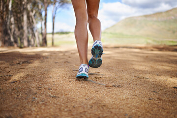 Legs, sneakers and person running in nature, woods or forest with fitness for health and wellness...