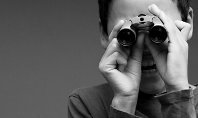boy looking through binoculars on gray background stock photo	