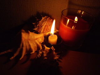 Two burning candles and shells.