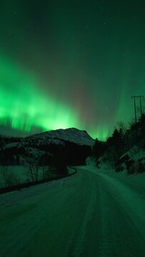 The roads we take. On the roads up to the mountain, an aurora is dancing so brightly it colors the entire landscape.