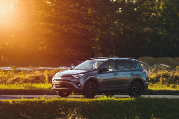 Fototapeta na wymiar An adventurous drive as a crossover SUV car speeds along a highway under the beautiful sunlight and surrounded by nature beauty.
