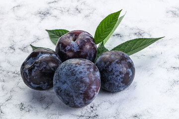 Raw purple plums heap with leaves