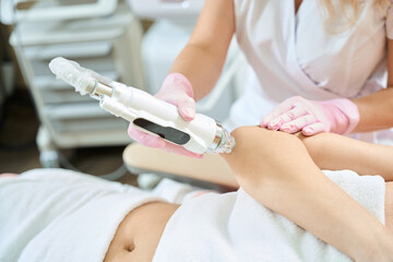 Cropped of female cosmetologist doing microneedle rf lifting of woman elbow skin