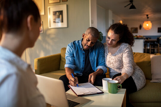 Couple signing documents at home with consultant